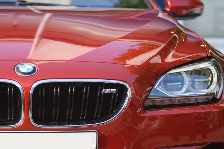 Detailed front view of a red luxury sports BMW car highlighting the hood and headlight.