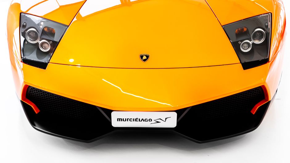 Vivid front view of an orange Lamborghini Murciélago SV supercar on display in a museum.
